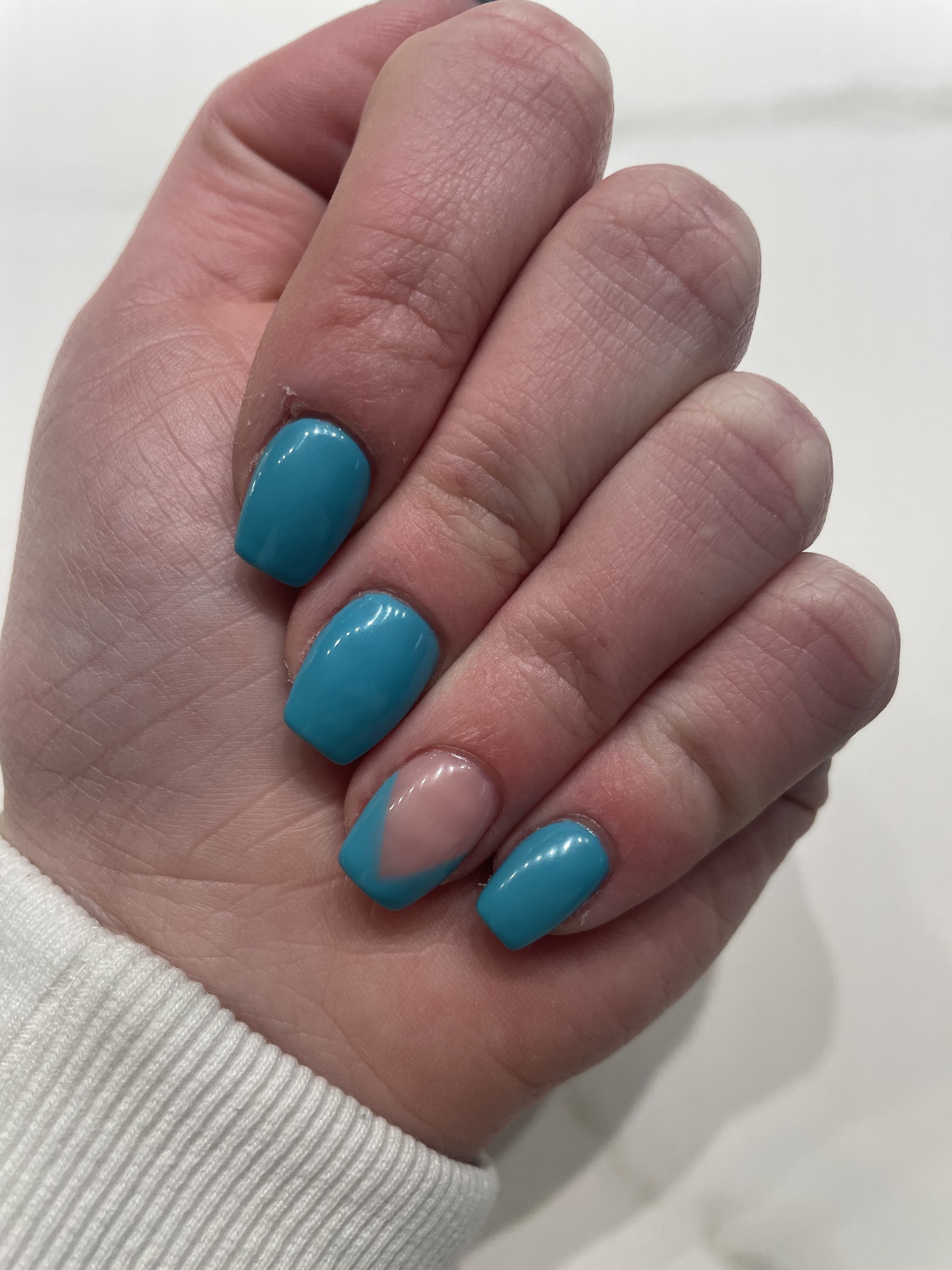 Turquoise nagels, dezelfde kleur als de muur van de salon, met een French tip op de ringvinger